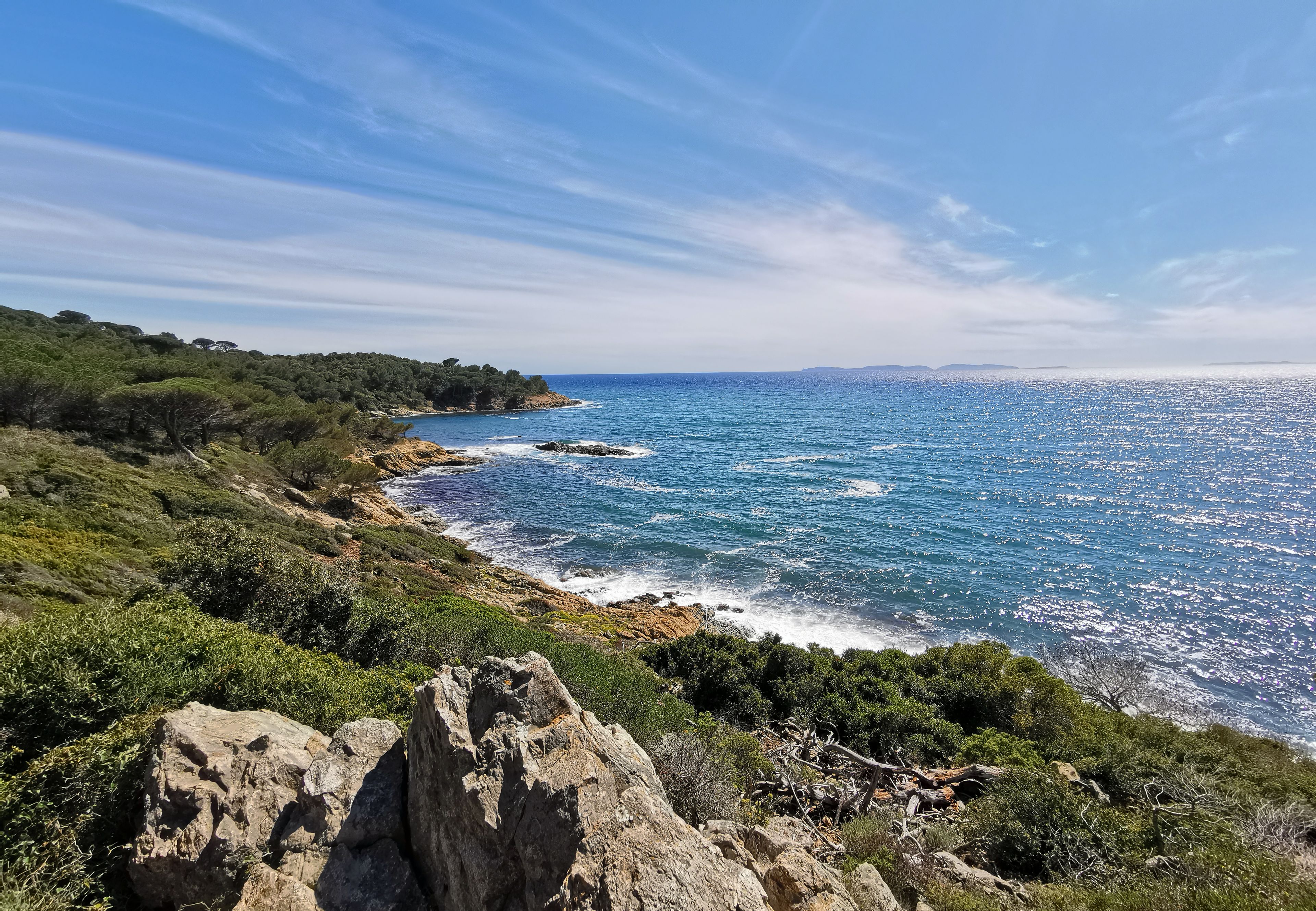 A coastal landscape with rocky terrain and dense vegetation.