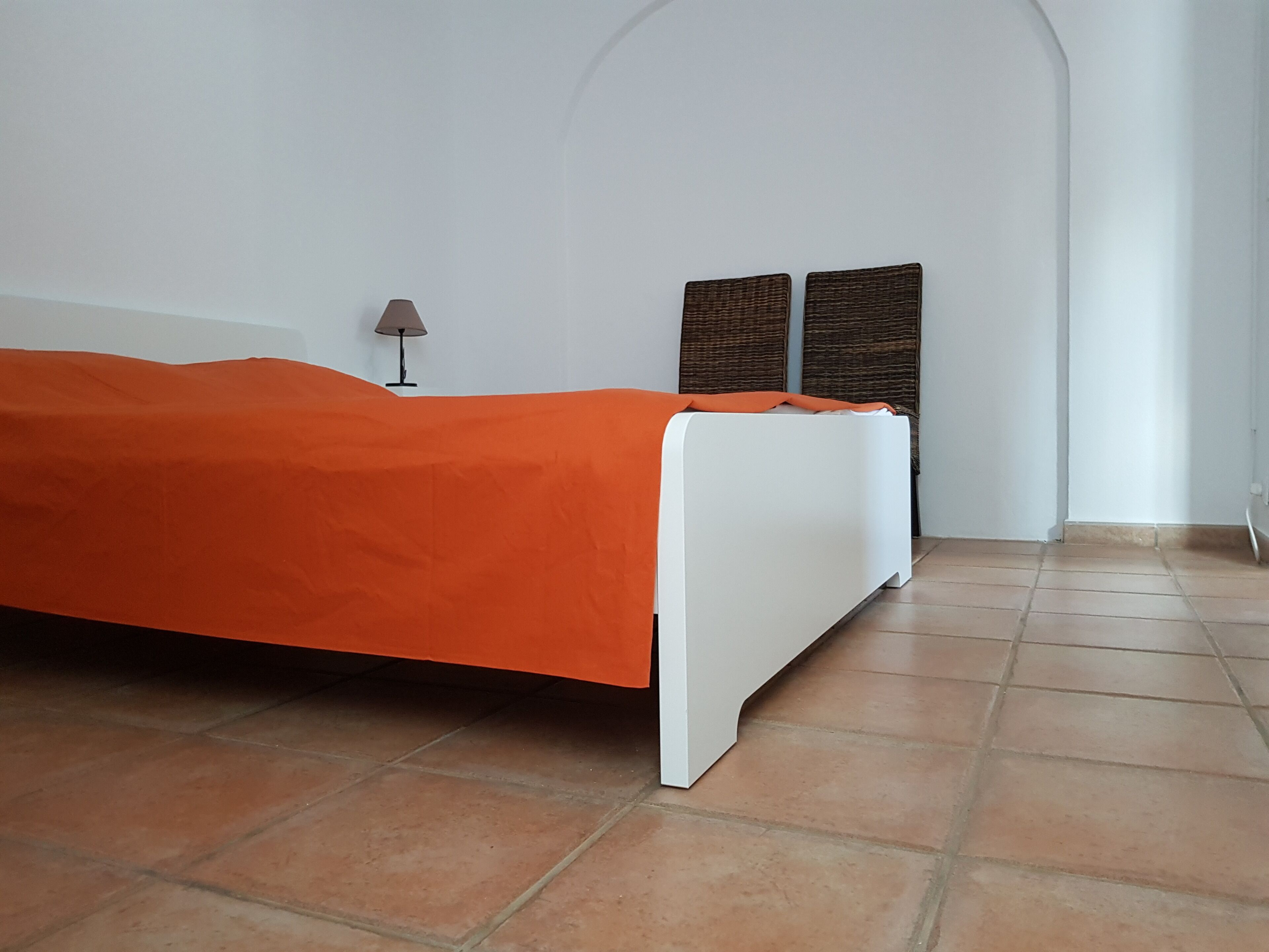 Ein Zimmer mit einem Bett, einer Lampe und zwei gewebten Wandteppichen.