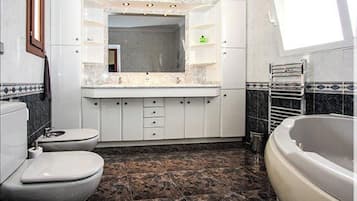Een bad/douchecombinatie, een haardroger, een bidet, handdoeken