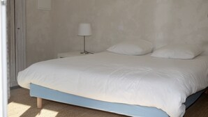 A bedroom with a bed, a nightstand, a lamp, and a wall-mounted light switch. - Superb seaside villa, warm and fully equipped (Vieux-Boucau-Les-Bains)