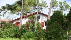 A white building with a red roof, surrounded by trees and bushes. - Superb seaside villa, warm and fully equipped (Vieux-Boucau-Les-Bains)
