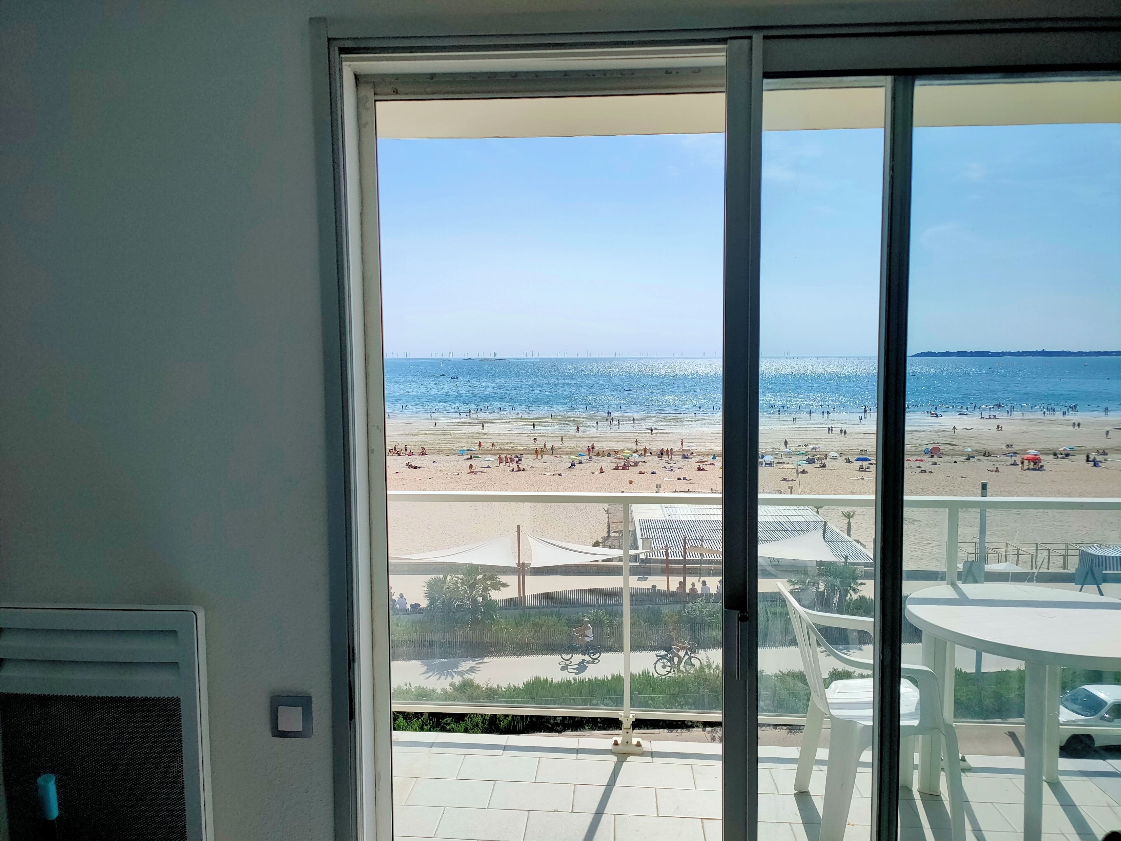 Uitzicht vanaf een balkon op een strand, met een heldere lucht.