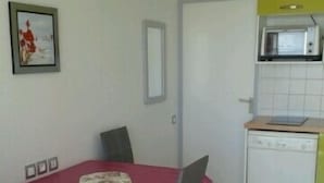 A compact kitchen with a microwave, a small sink, and a table with chairs.