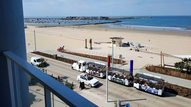 A beachside view with a parking area, a food truck, and a view of the ocean.