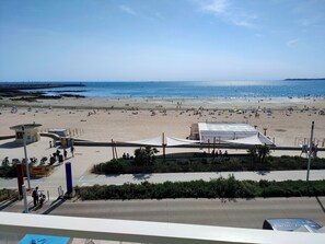 Una platja amb cel serè, sorra daurada i algunes ombrel·les.