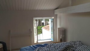 Un dormitorio con tragaluz, cama con ropa de cama estampada, radiador y vistas al exterior.