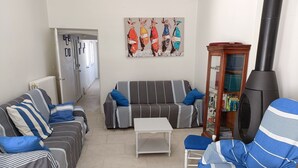 Una sala de estar con sofás a rayas, una mesa de centro blanca y una chimenea.