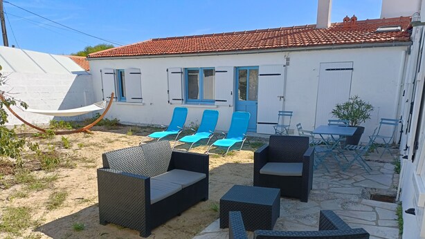 Un patio con muebles de mimbre, una hamaca y un edificio con techo de tejas.