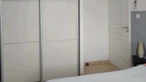 A bedroom with a bed, a wardrobe, a door, and an air conditioning unit.