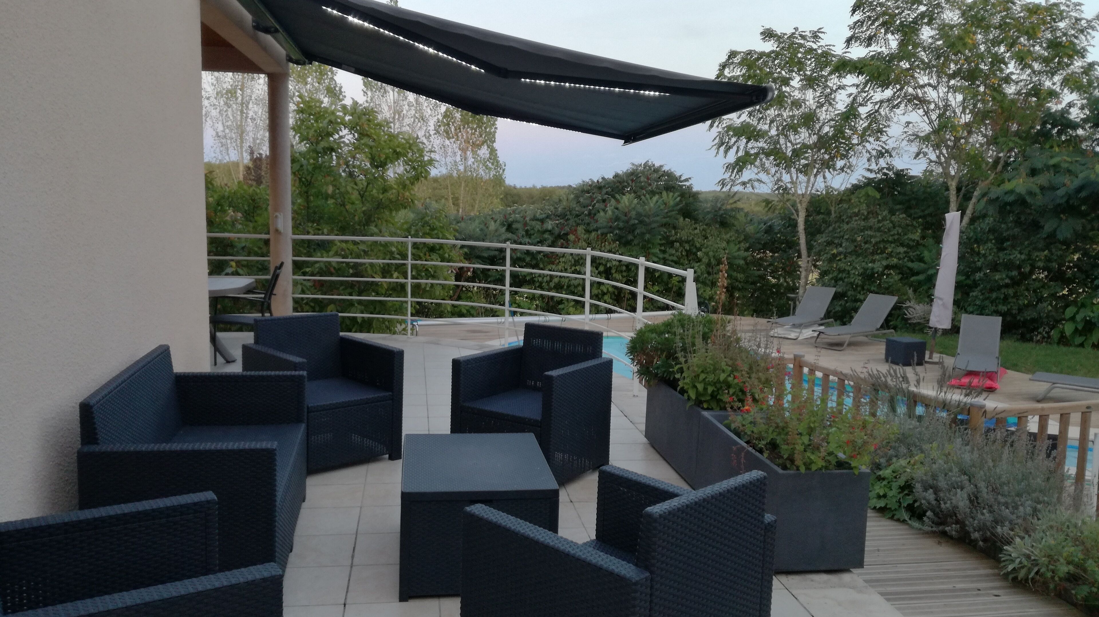 An outdoor patio with dark wicker furniture, a pool, and a white railing.