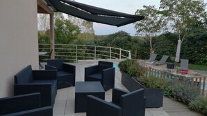 An outdoor patio with dark wicker furniture, a pool, and a white railing. - GITE NEAR CAHORS WITH PRIVATE HEATED POOL (Le Montat)
