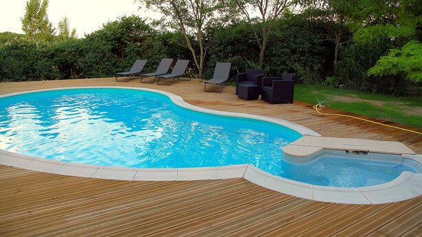 A swimming pool with a wooden deck, lounge chairs, and a hot tub. - GITE NEAR CAHORS WITH PRIVATE HEATED POOL (Le Montat)