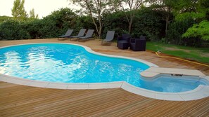 Piscina amb terrassa de fusta, gandules i banyera hidromassatge.