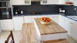 A modern kitchen with white cabinetry, a wooden island, and a bowl of oranges. - GITE NEAR CAHORS WITH PRIVATE HEATED POOL (Le Montat)
