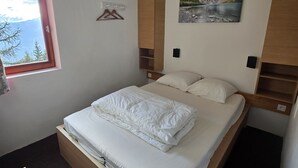 Une chambre à coucher avec un lit, une fenêtre, un tableau et une armoire en bois.