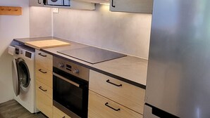Une cuisine moderne avec des meubles en bois, un réfrigérateur en acier inoxydable, un four encastré et un lave-linge.
