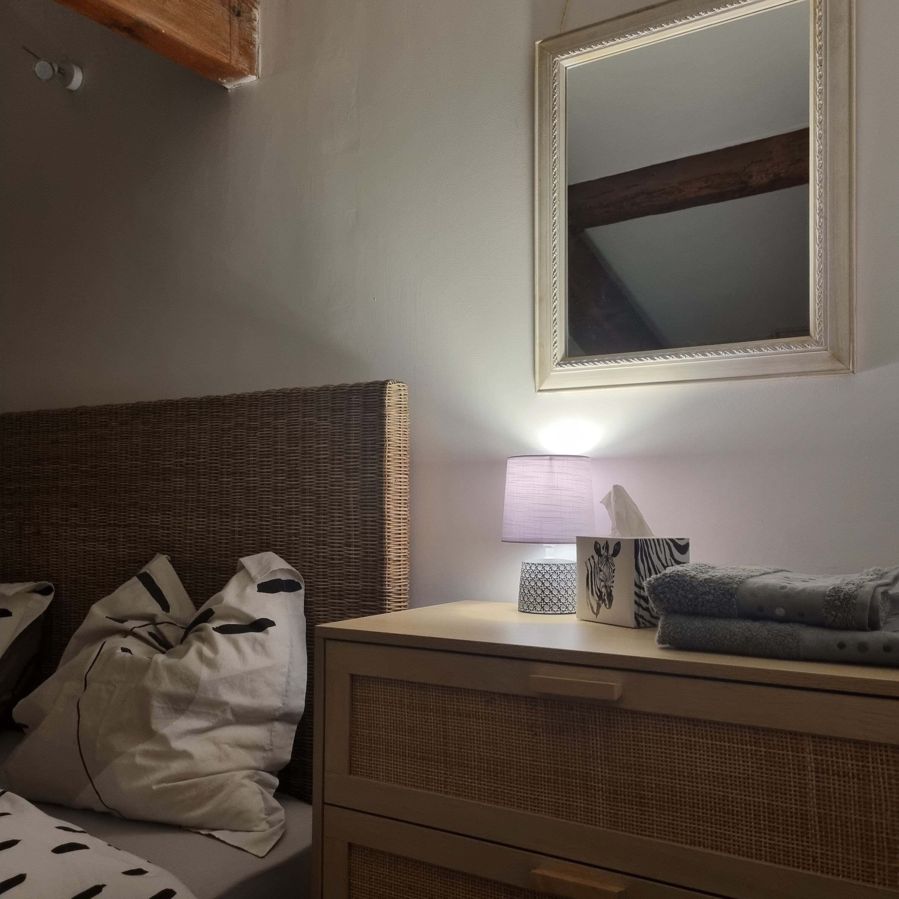 Une chambre à coucher avec un lit, une table de chevet avec une lampe, un miroir et une commode.