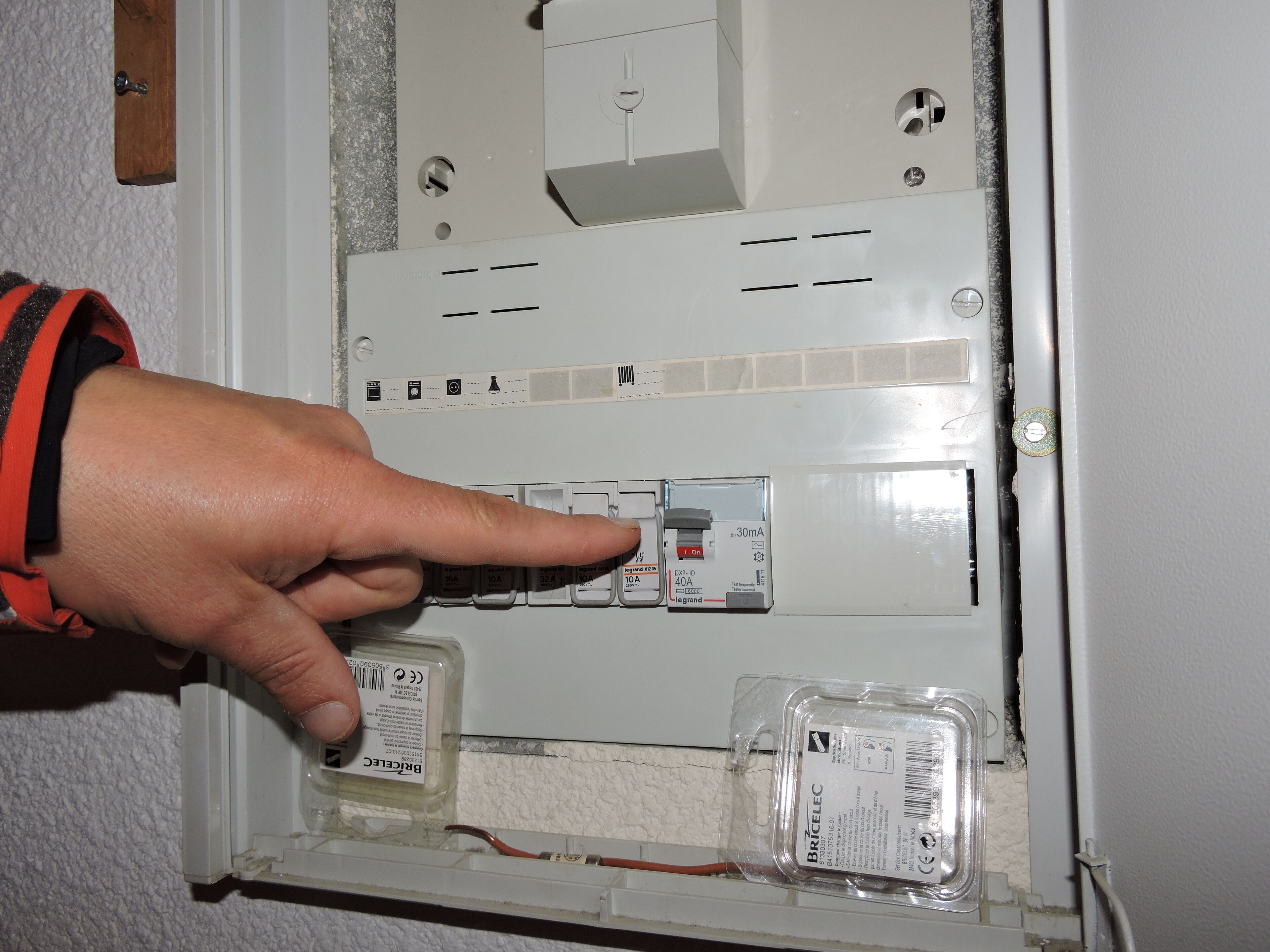 A hand pointing to a switchboard with multiple switches and a label indicating a 30mA current rating.