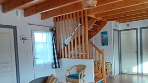 Un'ampia zona giorno con soffitto in legno, una scala e vista sull'esterno.
