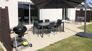 An outdoor patio with a table and chairs, a grill, and a large umbrella. - Pretty house with enclosed garden close to amenities in ERDEVEN. (Erdeven)
