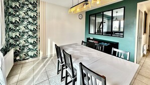 A dining area with a long table, chairs, a clock, and a window with a view. - Seaside escape - House with private SPA in Erquy (Erquy)