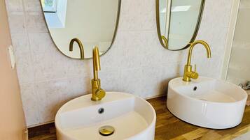 Twee witte wasbakken met gouden kraanwerk en spiegels erboven in een badkamer.