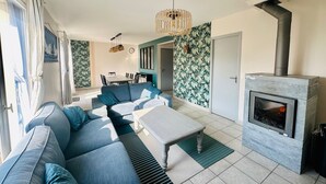 A modern living room with a sectional sofa, a fireplace, and a dining area in the background. - Seaside escape - House with private SPA in Erquy (Erquy)
