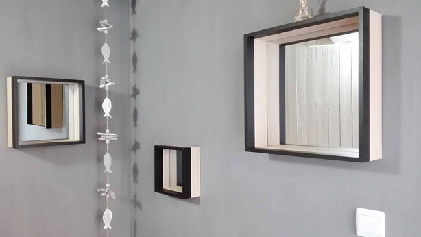 A wall with three framed mirrors of varying sizes and a decorative string of white flowers. - Bright duplex apartment in Belle Ile en Mer  (Le Palais)
