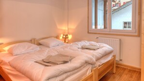 A double bed with white bedding, a nightstand with a lamp, and a window with a view of a building. - Cottage with magnificent view of the Lake in Gérardmer, 8 people (Gérardmer)