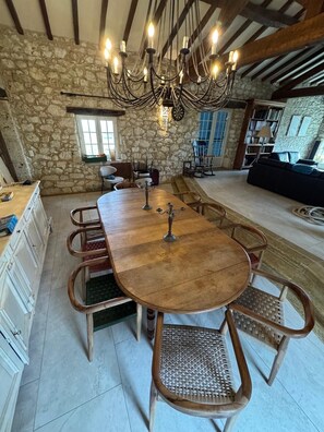 Un comedor rústico con una gran mesa de madera, sillas de mimbre y un fondo de pared de piedra.
