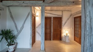 Un couloir avec des poutres apparentes, une plante en pot et une lampe.