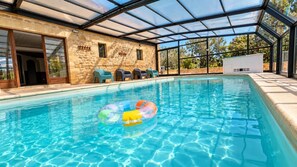 A swimming pool with a glass enclosure, stone walls, and a few chairs. - Rental Residence with 2 swimming pools, jacuzzi, sauna, billiards (NABIRAT)
