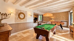 A billiards room with a pool table, a wooden table, and a billiard cue rack.