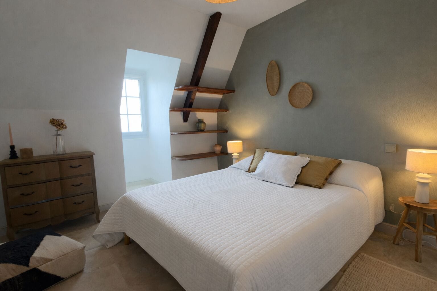Une chambre à coucher avec un grand lit, une commode en bois et des étagères.