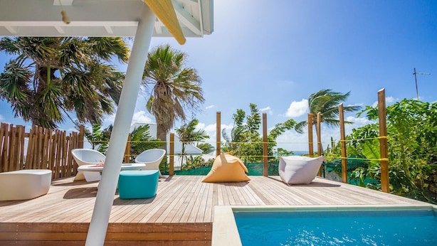 A wooden deck with a pool, lounge chairs, and a view of palm trees. - Villa Passion 4 people, sea view, in the heart of the Riviera of the islands of Guadeloupe (Sainte Anne)