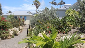 A pathway leading to a building surrounded by lush greenery and palm trees. - Villa Passion 4 people, sea view, in the heart of the Riviera of the islands of Guadeloupe (Sainte Anne)