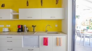 A kitchen with white cabinets, a yellow wall, a sink, and a coffee maker. - Villa Passion 4 people, sea view, in the heart of the Riviera of the islands of Guadeloupe (Sainte Anne)