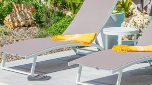Two lounge chairs with cushions, a small round table, and a potted plant in a garden setting. - Villa Passion 4 people, sea view, in the heart of the Riviera of the islands of Guadeloupe (Sainte Anne)