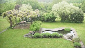 A garden with a pond, a pergola, and a table and chairs.