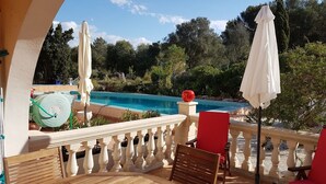 Ein Balkon mit Pool, roten Stühlen und einem Tisch.