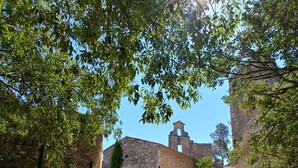 A stone building with a red door and a bell tower, surrounded by trees and a gravel path. - Villa, private heated pool, beautiful view of the Alpilles (Eygalières)