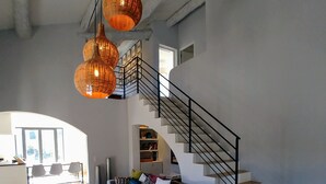 A spacious living area with a grey sectional sofa, a wooden coffee table, and a staircase with a black railing. - Villa, private heated pool, beautiful view of the Alpilles (Eygalières)