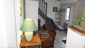 A room with a wooden desk, a lamp, a laptop, a chair, a staircase, and a plant. - For a stay in 2 very quiet in a tufa house in Anjou (Gennes-Val De Loire)