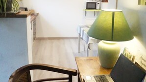 A small kitchen with a microwave, a table with a laptop, and a green lamp. - For a stay in 2 very quiet in a tufa house in Anjou (Gennes-Val De Loire)