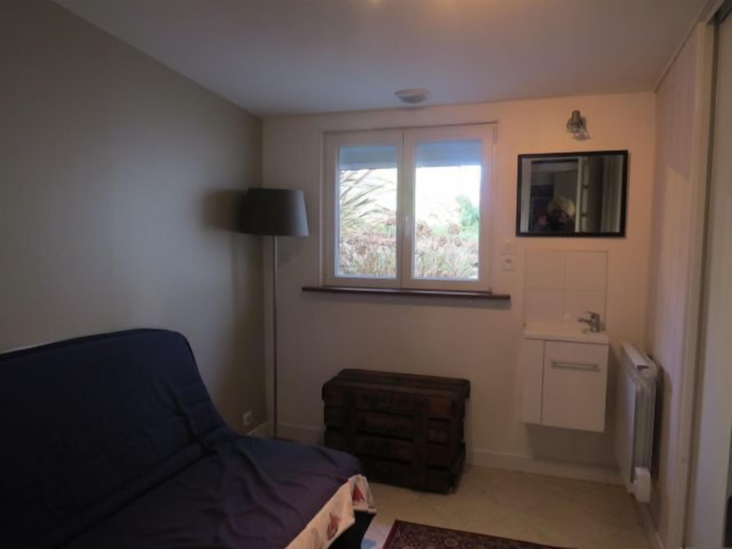 Une chambre à coucher avec un lit, une commode, une fenêtre et un radiateur.