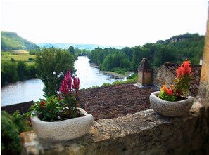 Enjoy a serene riverside view from this stone terrace, overlooking a gently flowing river and lush greenery.