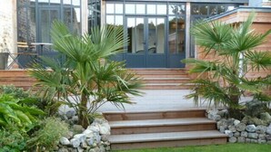 Una casa moderna con una scala in pietra che conduce a una porta in legno, immersa nel verde e circondata da un prato curato.