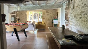 A cozy living room with a foosball table, a yellow armchair, and a coffee table with books and a vase. - Basque farmhouse with swimming pool (Mouguerre)