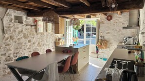 A rustic kitchen with stone walls, wooden beams, and a dining area with a table and chairs. - Basque farmhouse with swimming pool (Mouguerre)