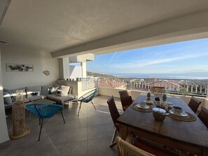 Un grand balcon équipé d’une table à manger, de chaises et d’un canapé.